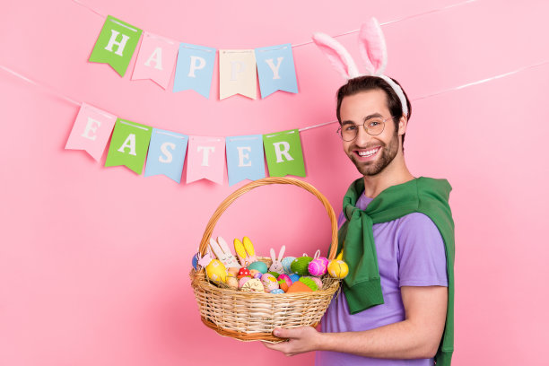 好心情可爱的男人的侧面照片与兔子耳朵抱复活节篮子庆祝节日孤立在粉红色的背景图片下载