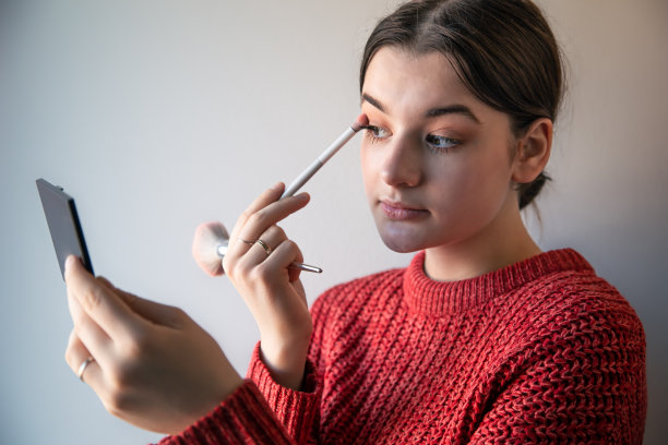 一个年轻女人的肖像，用刷子化妆的过程。图片下载