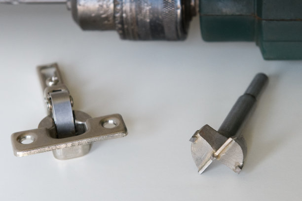 家具安装配件工具。铰链固定在一个现代橱柜上。图片下载