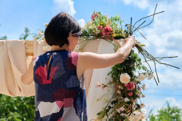 在婚礼拱门上装饰花卉的女人图片下载
