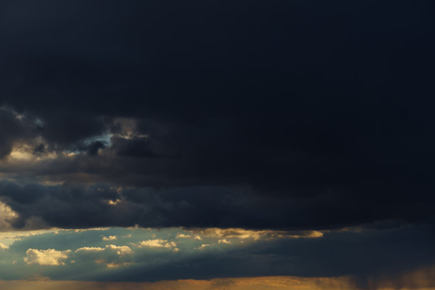 美丽的戏剧性的天空，明亮的阳光和黑色的轮廓云作为背景图片下载