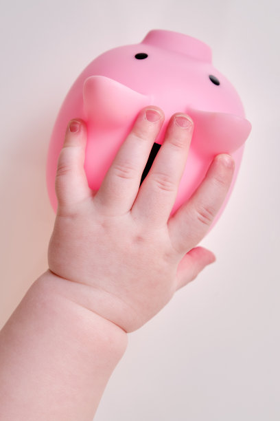 婴儿手和粉色储蓄罐，特写镜头。孩子的手指和白色背景上的物体图片下载