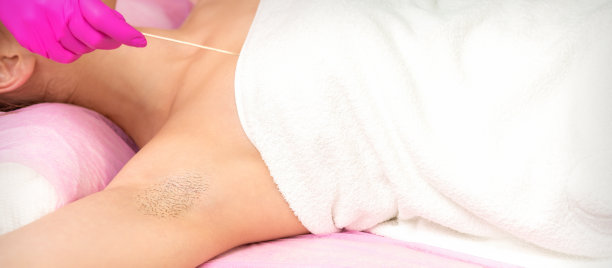 用刮刀戴手套，在水疗中心脱毛女性腋下。图片下载