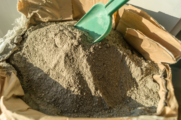 灰砂混凝土干拌，装在打开的纸袋中。平整墙壁和地板用混凝土干粉。自己动手修理房子。DIY。有选择性的重点图片下载