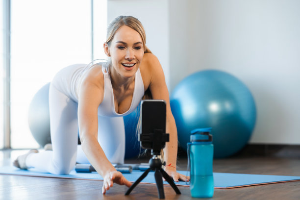 漂亮的健身女人在网上直播。nGirl在室内用智能手机录制视频课程图片下载