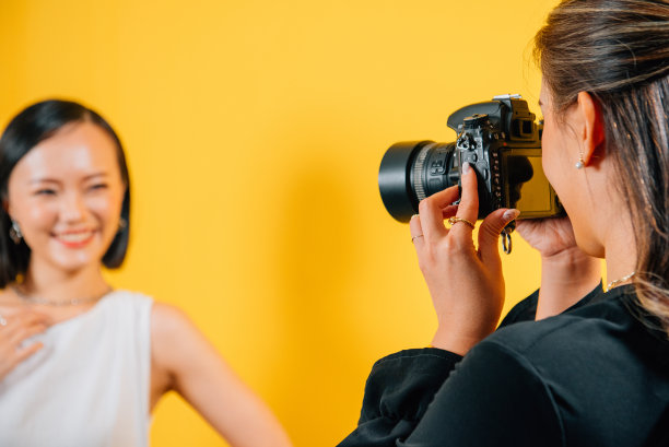 美丽的女性被朋友拍摄在黄色背景拍摄工作室图片下载