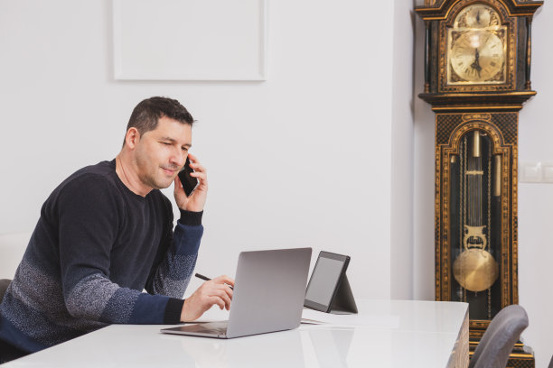 他在办公室里用笔记本电脑和平板电脑工作。图片下载