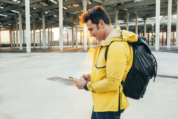 英俊开朗的男子在日落时分在户外使用智能手机图片下载