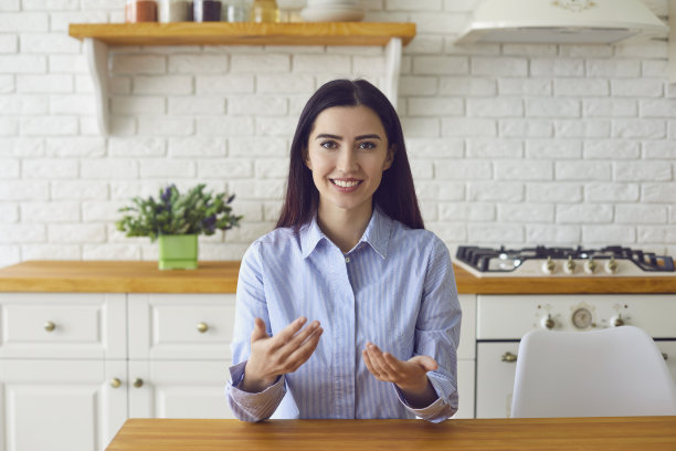 年轻女性的肖像通过网络交流或参与在厨房的商业视频会议图片下载
