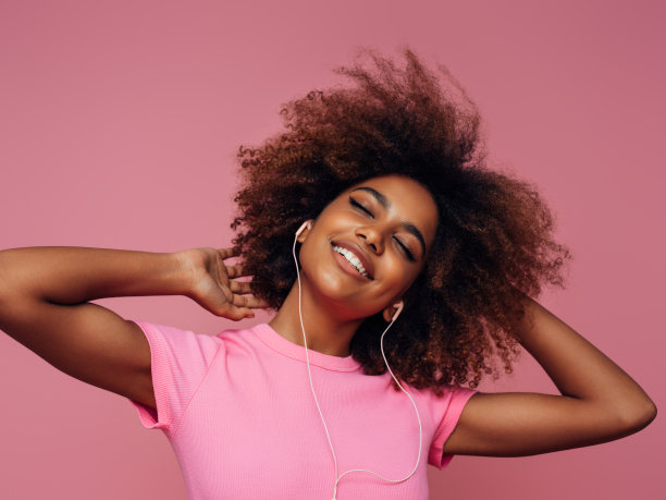 年轻的卷发女孩带着耳机的照片图片下载