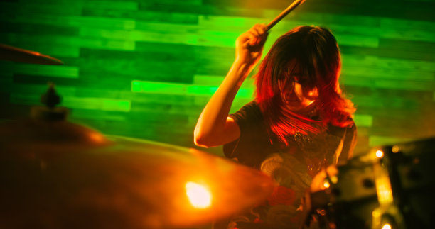 美丽的女孩在摇滚音乐会的舞台上热情地打鼓图片下载