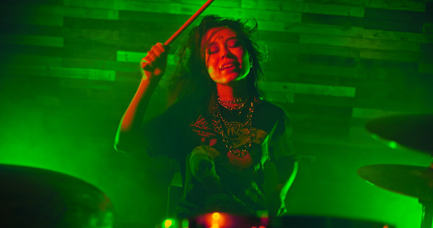 美丽的女孩完美的肖像在舞台上演奏鼓在摇滚表演图片下载