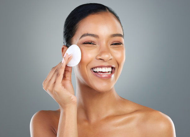 这张照片拍摄的是一位美丽的年轻女子用化妆棉清洁她的脸图片下载