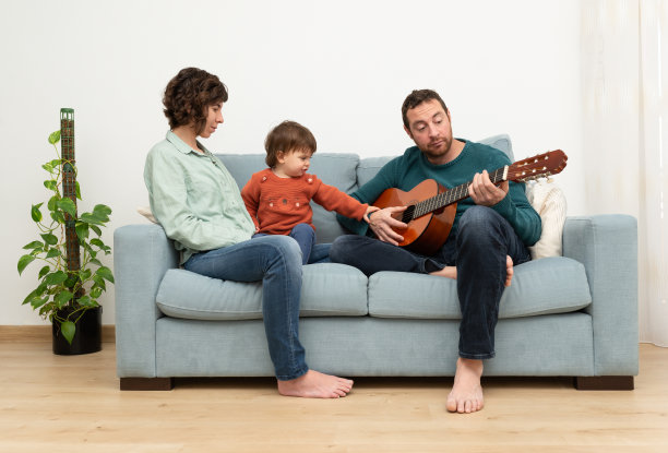 家庭(母亲，父亲和蹒跚学步的孩子)一起享受音乐。图片下载