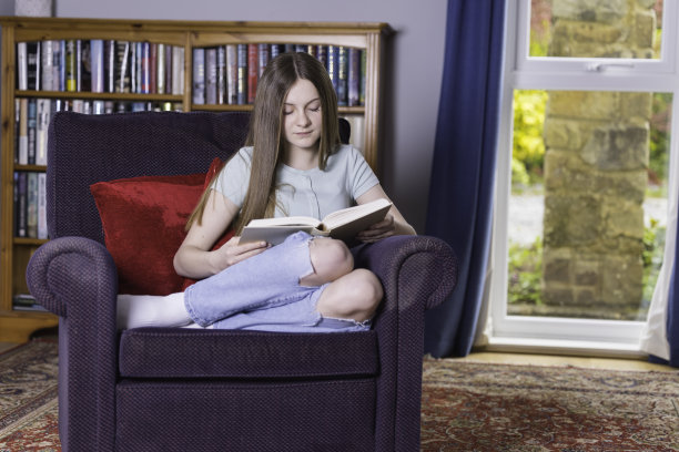 小女孩坐在她最喜欢的椅子上看书图片下载