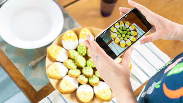 美食博主用智能手机拍摄美食。一位网红为复活节拍摄了可爱的小鸡形状的冰糖饼干。和孩子们一起为复活节做有趣的烘焙。图片下载
