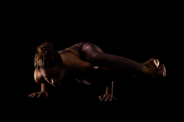 健身妇女练习瑜伽姿势。侧面灯光半剪影的女孩在黑色背景的工作室做练习。图片下载