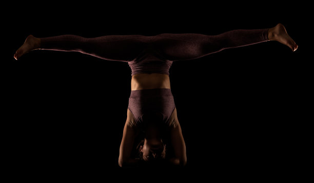 健身妇女练习瑜伽姿势。侧面灯光半剪影的女孩在黑色背景的工作室做练习。图片下载