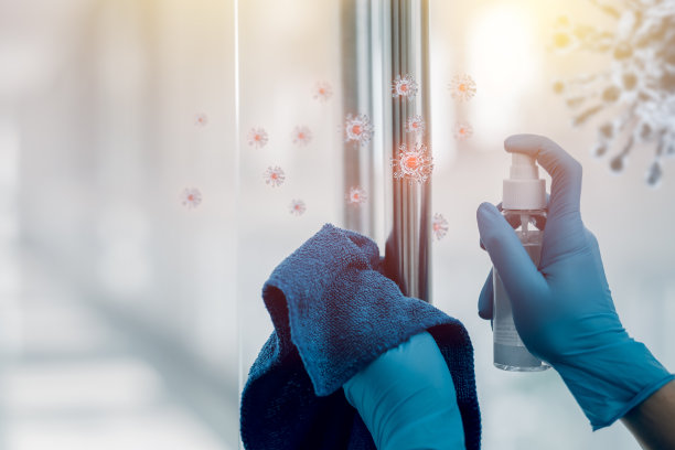 手戴手套，用酒精喷雾擦拭清洁的门把手，以防止新冠病毒的传播。保健消毒理念。图片下载
