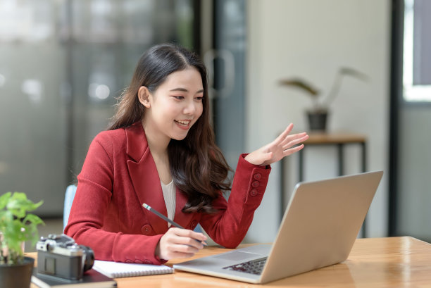 年轻的亚洲女商人用笔记本电脑与客户视频通话，对着屏幕挥手。漂亮的女学生用平板电脑学习视频聊天。图片下载