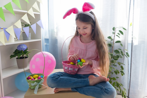 穿着粉红色t恤和兔子耳朵的女孩在一个装饰着气球的房间里庆祝复活节图片下载