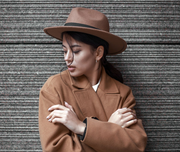 年轻的商业女士在复古风格的背景石墙棕色米色外套和经典的帽子，在自然光线下孤立的肖像图片下载