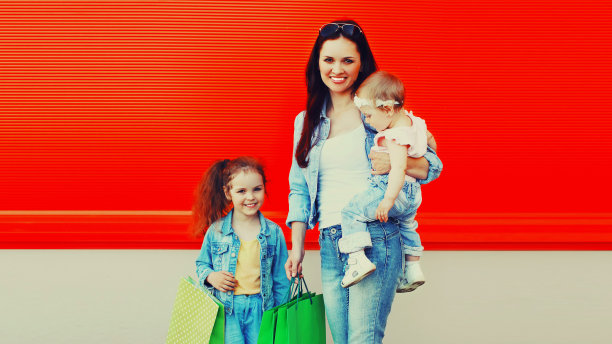 幸福微笑的母亲和孩子的肖像，在红色背景的城市购物袋图片下载