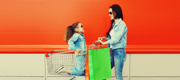 快乐的微笑的母亲和小女孩的购物车和购物袋在城市图片下载