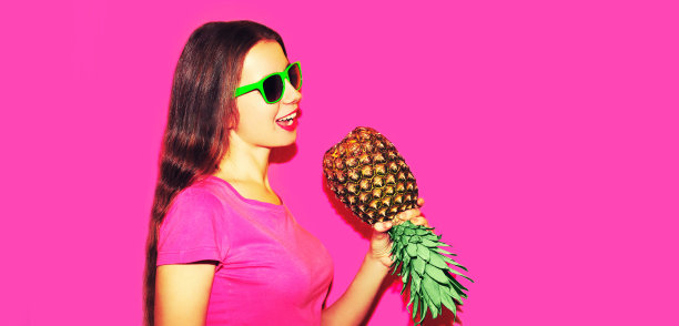 时尚肖像的女人唱歌与菠萝戴着太阳镜在粉红色的背景图片下载