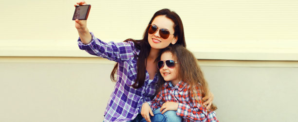 幸福微笑的母亲和孩子一起在城市里用智能手机自拍的照片图片下载