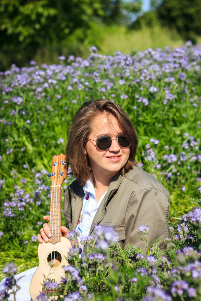 快乐的年轻微笑的女人与四弦琴户外的肖像图片下载