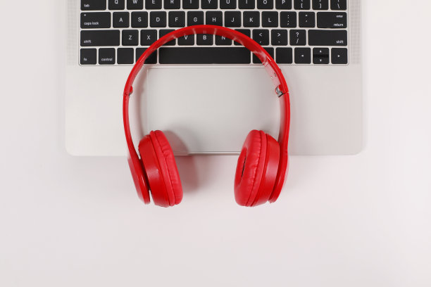红色耳机和笔记本电脑放在白色的表面上图片下载