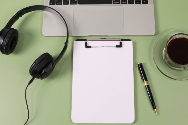 现代绿色办公桌椅，配有笔记本电脑、记事本、笔、眼镜、耳机。平躺，顶视图，复制空间"n图片下载