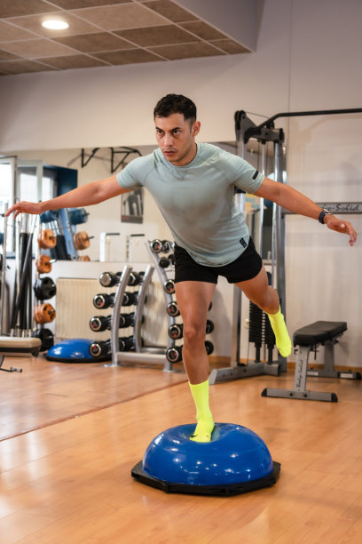 人像一名白人男子在体育馆的橡胶球上为脚踝做平衡练习，健康健康的生活做运动图片下载
