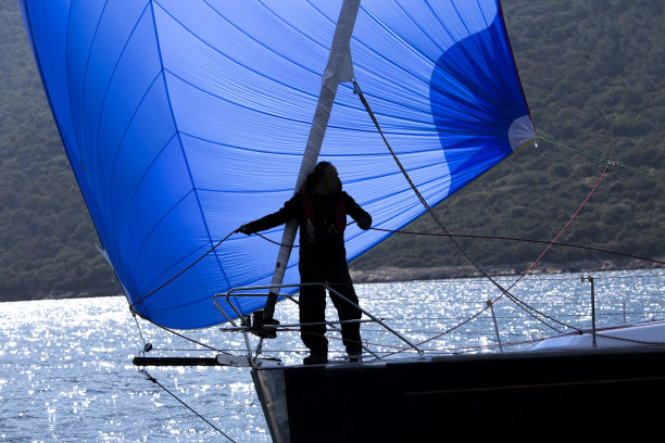 在调整蓝色帆绳的帆船上的人的轮廓图片下载