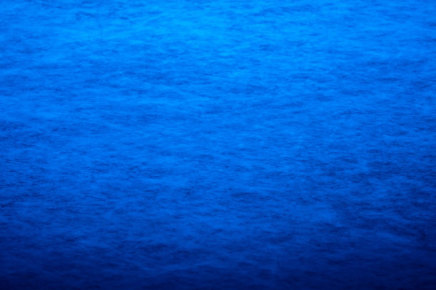 蓝色灯光下的溜冰场、曲棍球或花样滑冰运动场馆表面的背景和纹理。体育场的表面布满了划痕、条纹和溜冰痕迹。近距离图片下载