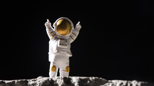 在岩石表面的宇航员。宇航员在漆黑的太空中。图片下载