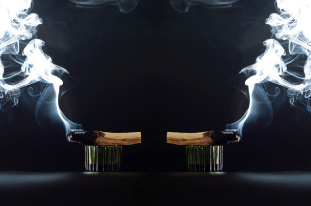 两根神圣的熏香帕罗桑托在黑色的背景上，迎面而来的光和大量的烟雾在框架的边缘，复制空间。焚香、疗愈、冥想、放松、宁静、安抚的概念。图片下载