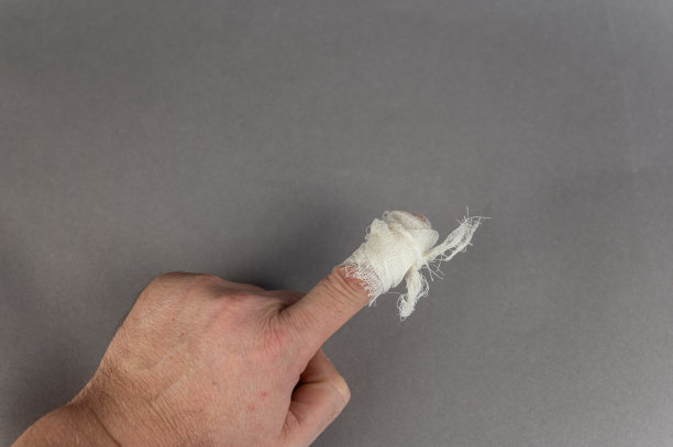 一个食指缠着绷带的成熟男人的手。那个人把手掌放在灰色的背景上。健康和医学。图片下载