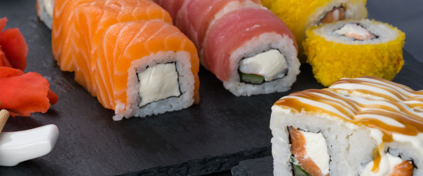 黑色的桌子上放着一张特写照片，上面是三文鱼、金枪鱼和天妇罗烤制的各种日本卷图片下载