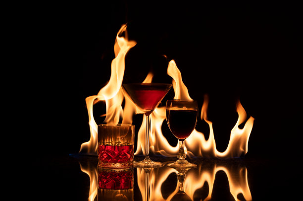 这是一款由葡萄酒、爱尔兰咖啡和美味的波旁威士忌组成的三重奏，金色火焰在反光的表面上流动图片下载
