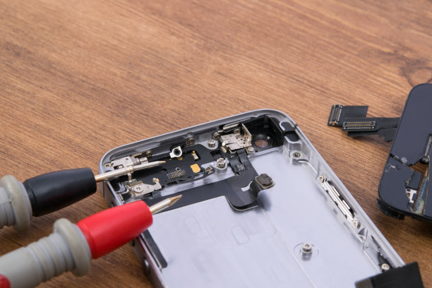 在一张木桌上，特写镜头，用智能手机测试器检修和更换电池图片下载
