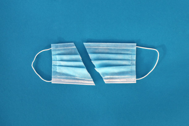 将医用口罩切成两部分，在浅蓝色的背景上。图片下载