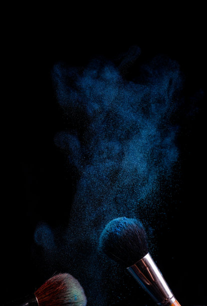 化妆刷上不同颜色的粉底，在黑色的背景上像太空灰尘一样图片下载