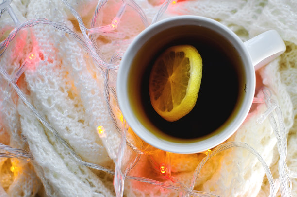 热柠檬茶在针织织物的背景与节日花环的灯。特写,有选择性的重点。图片下载