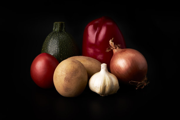 土豆，洋葱，红甜椒，番茄，西葫芦和大蒜在黑色的背景上。健康素食图片下载