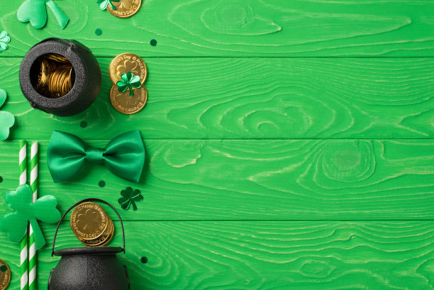 圣帕特里克节装饰的俯视图照片绿色领带蝴蝶结三叶草草三叶草形状的五彩纸屑和花盆与金币在孤立的纹理绿色木制桌面背景与空空间图片下载