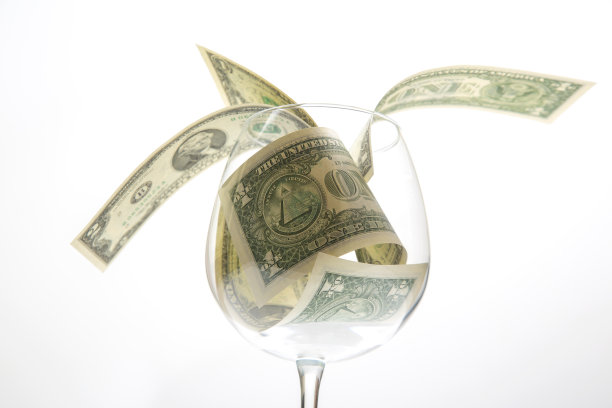 一张美元钞票躺在一个空酒杯里。葡萄酒行业的业务。酒精营销图片下载