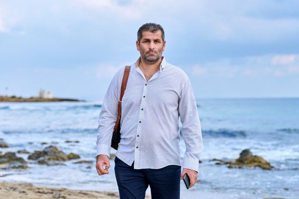 严肃、自信、成功、成熟的男人沿着海滩散步。图片下载