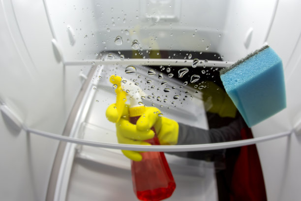 用清洁剂喷雾和海绵清洗冰箱内部。专业的食品保鲜厨房设备消毒服务图片下载
